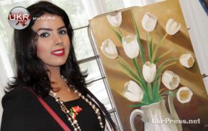 فنانة كويتية تقف إلى جانب لوحتها في المعرض