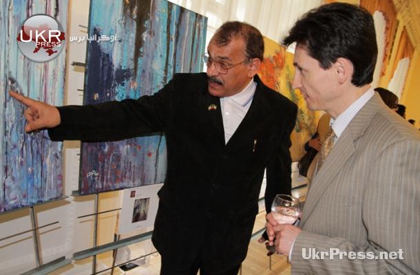 فنان كويتي يستعرض لوحته لأحد ضيوف المعرض